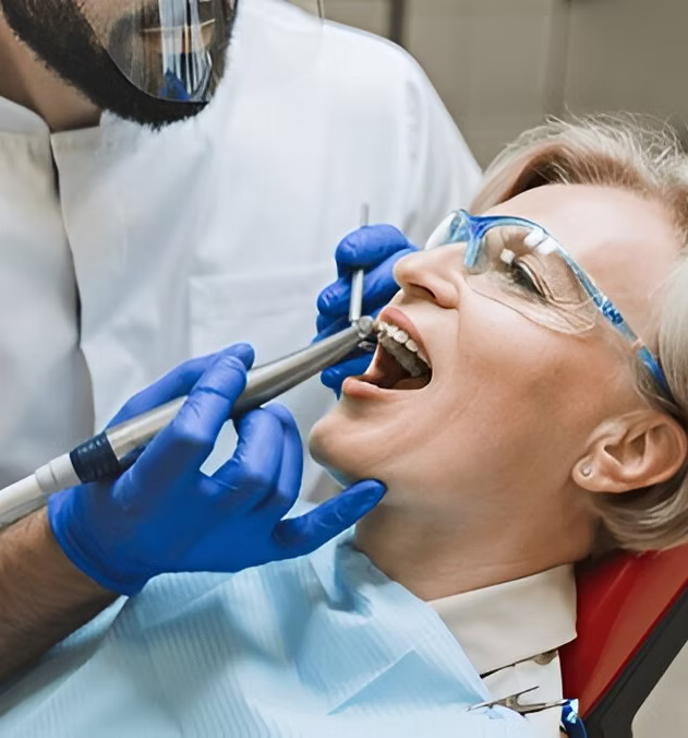 Dentist performing wisdom tooth removal on a patient wearing protective glasses
