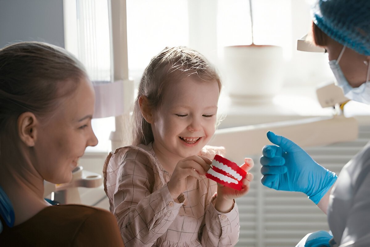 Child smiling during gentle dental visit with parent and dentist in Sherwood Park